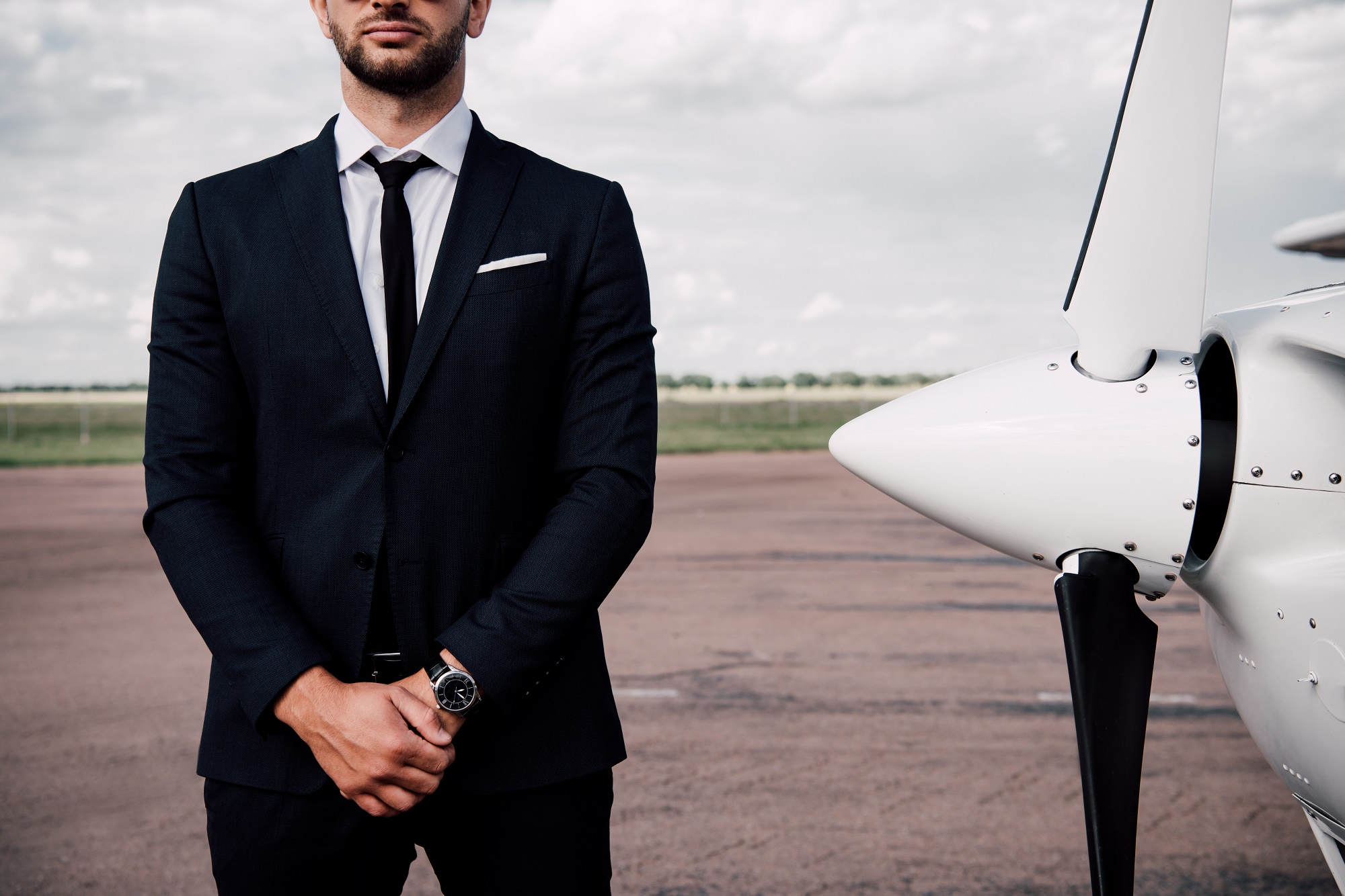 partial view of confident businessman in formal wear standing near plane